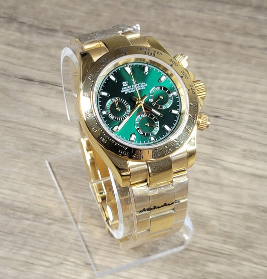 Gold wristwatch with green face on a wooden surface