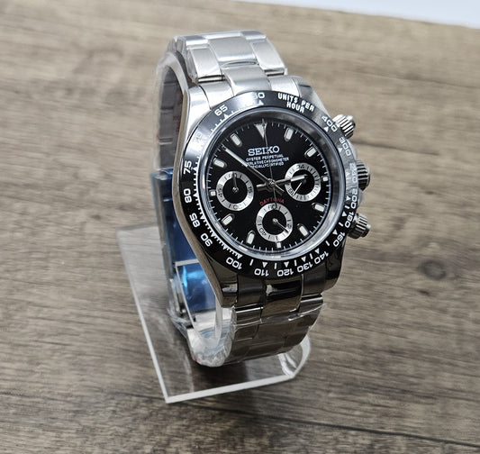 Seiko watch with black face and silver metal strap on a wooden surface