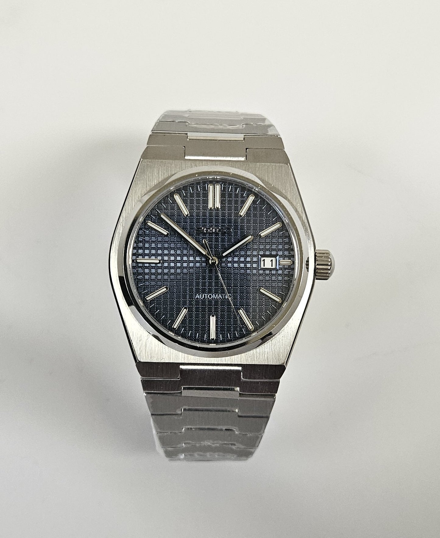 Silver wristwatch with dark face on white background