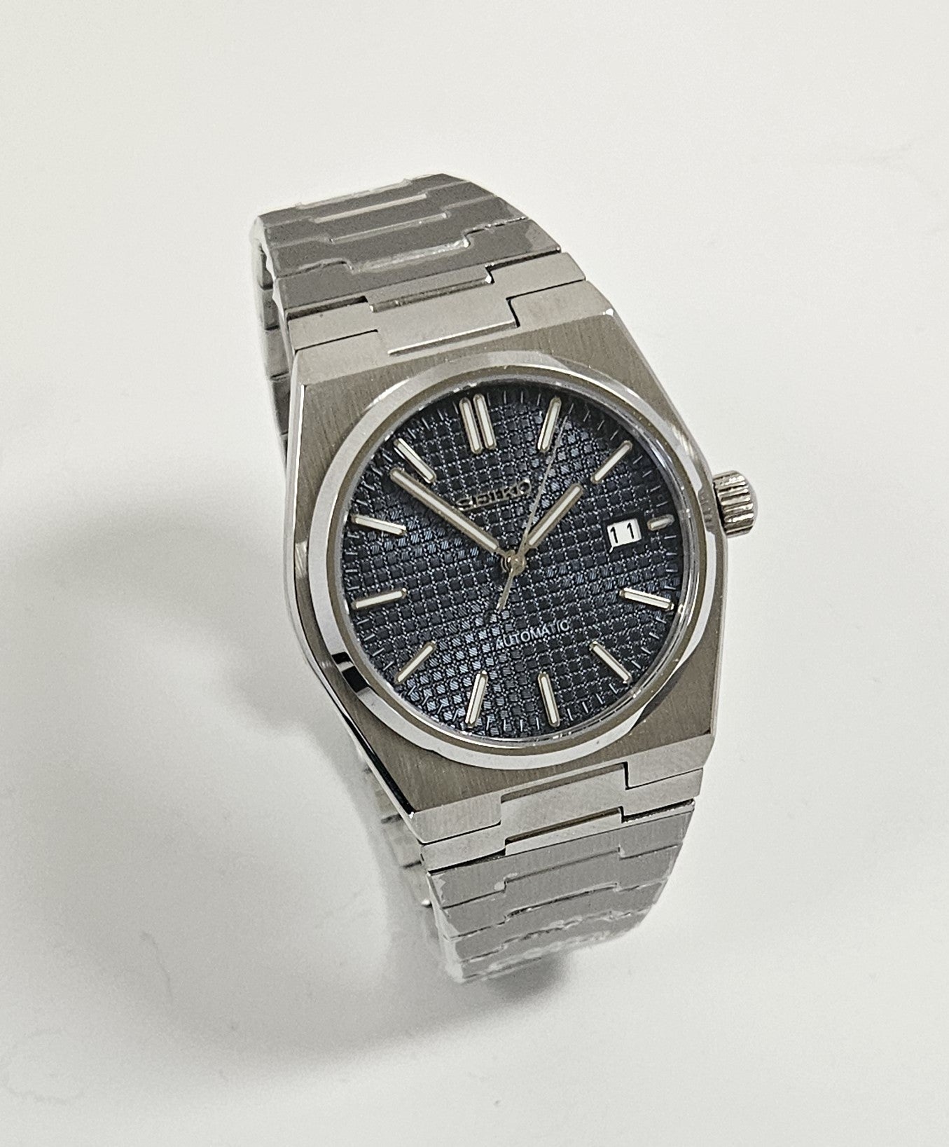 A Seiko watch with a blue dial and a stainless steel integrated bracelet, showcasing a PRX design.
