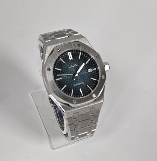 Luxury watch with metallic band and dark face on a clear stand.
