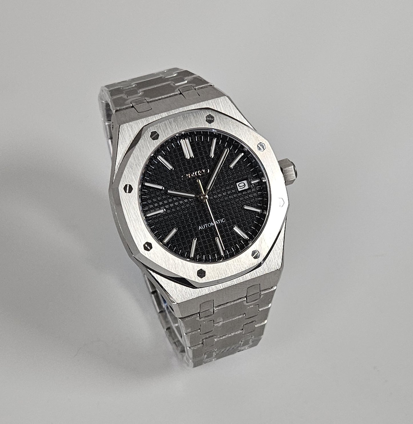 A black dial Royal Oak Seiko Mod watch with a stainless steel bracelet and a screw down case back.