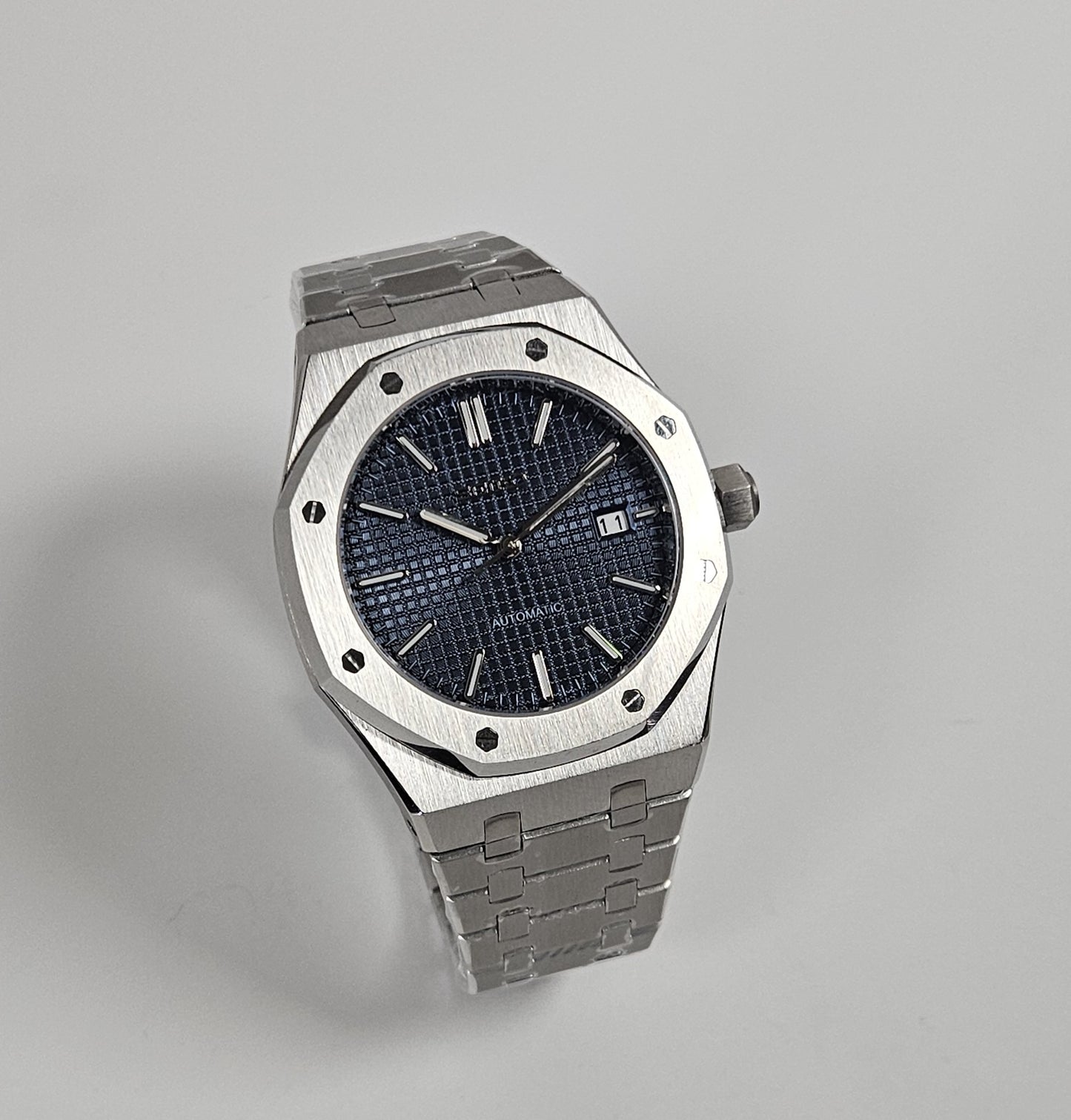 A black dial Royal Oak Seiko Mod watch with a stainless steel bracelet and a screw down case back.