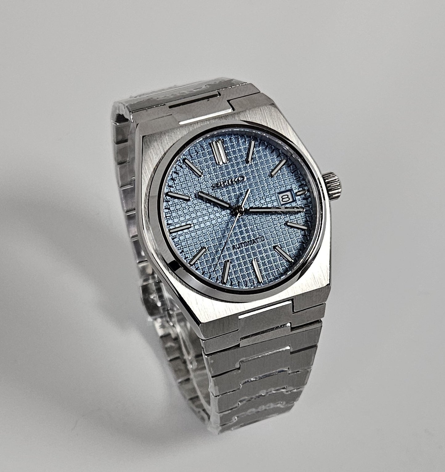 Silver wristwatch with a textured face on a gray background