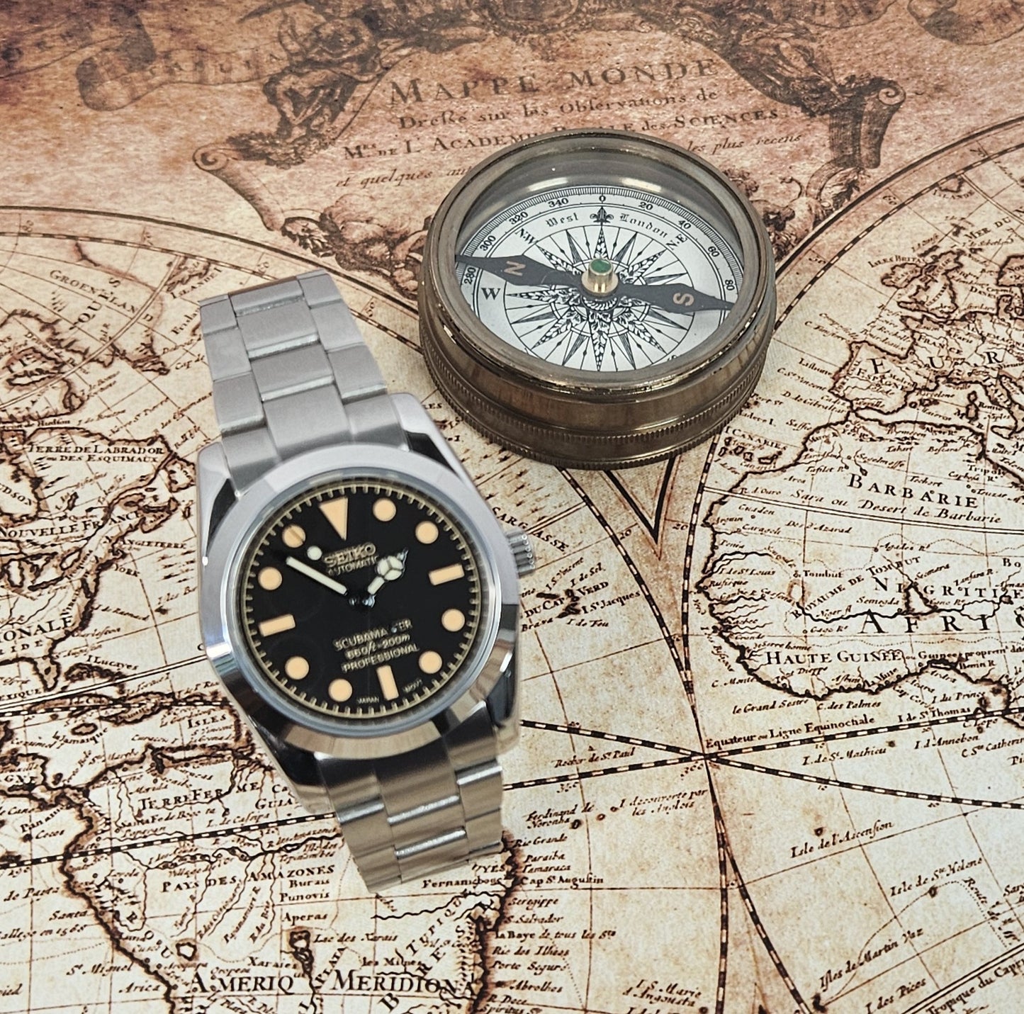 Vintage watch and compass on an old world map
