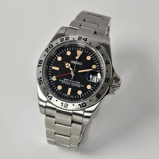 Silver Seiko watch with black dial on a light gray background