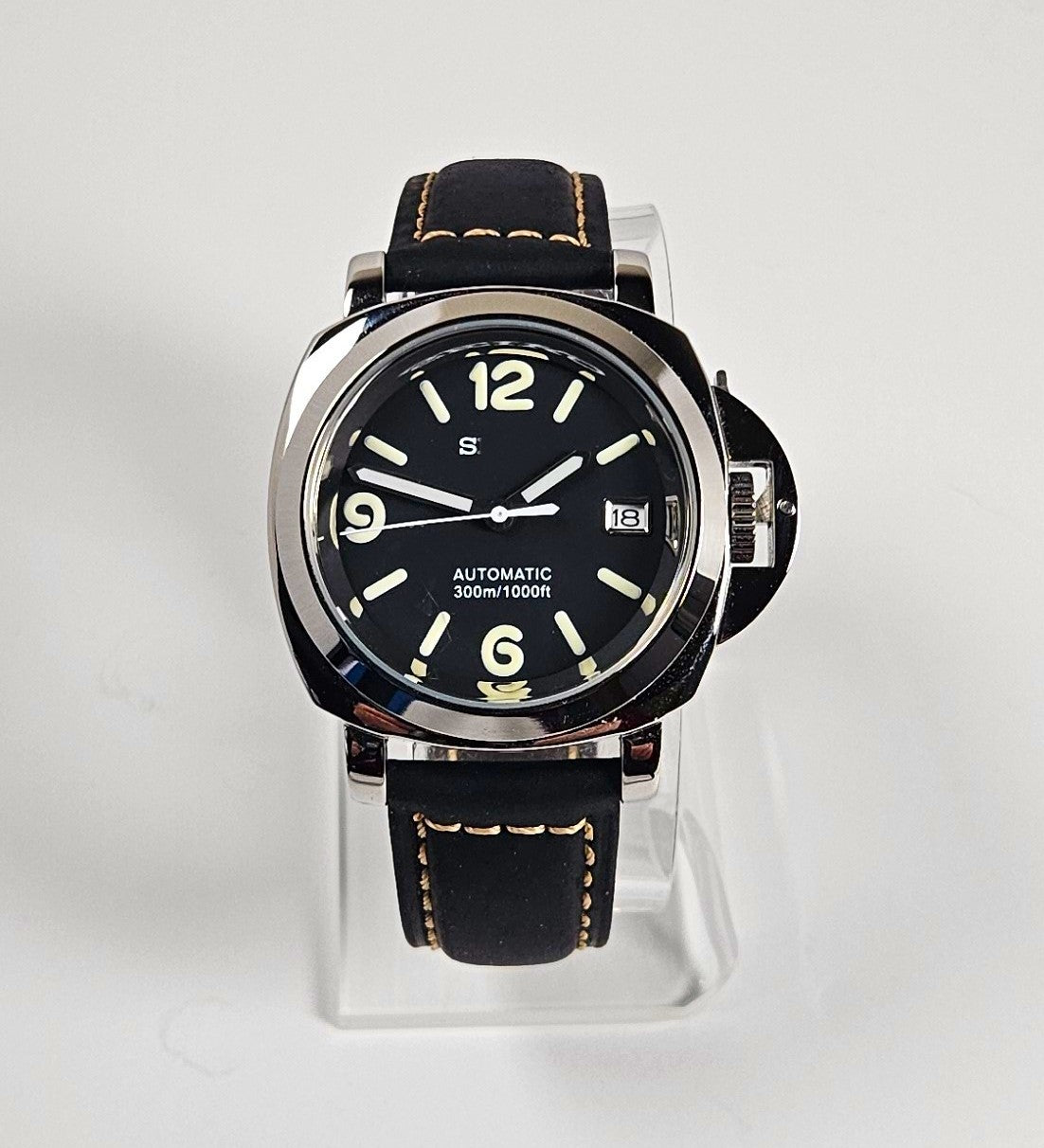 Black wristwatch with a clear stand on a light gray background