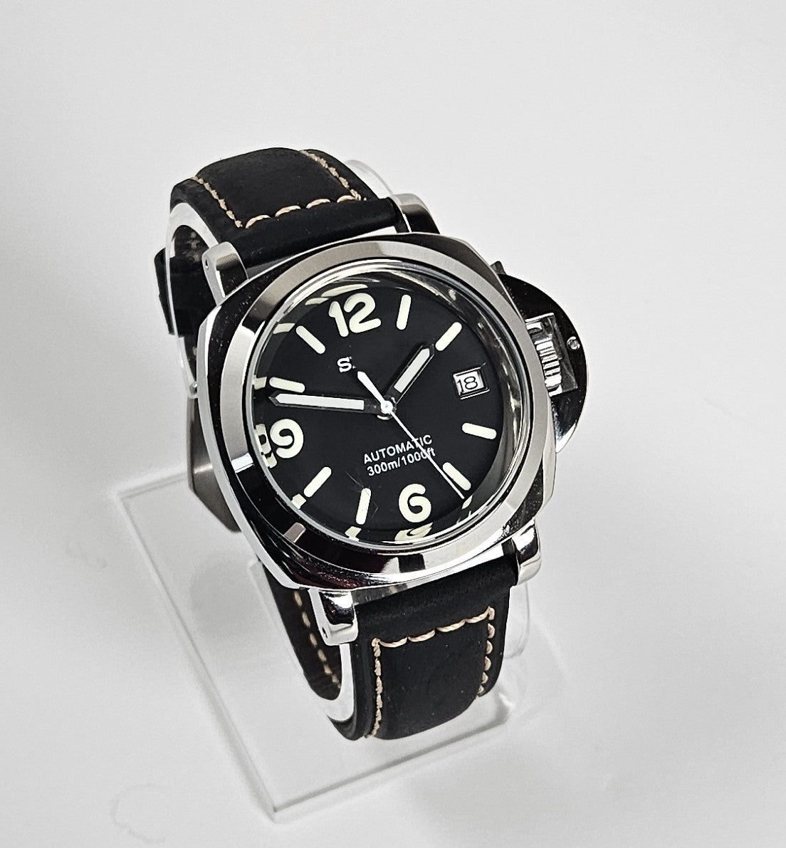 Black wristwatch with a clear stand on a light gray background