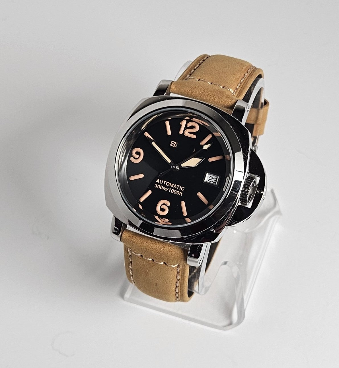 Watch with brown leather strap on a clear stand against a light gray background