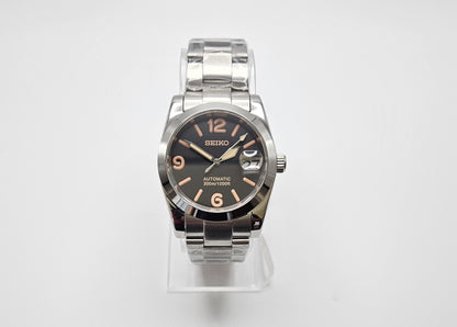 Seiko watch with silver case and black dial on a white background
