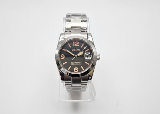 Seiko watch with silver case and black dial on a white background