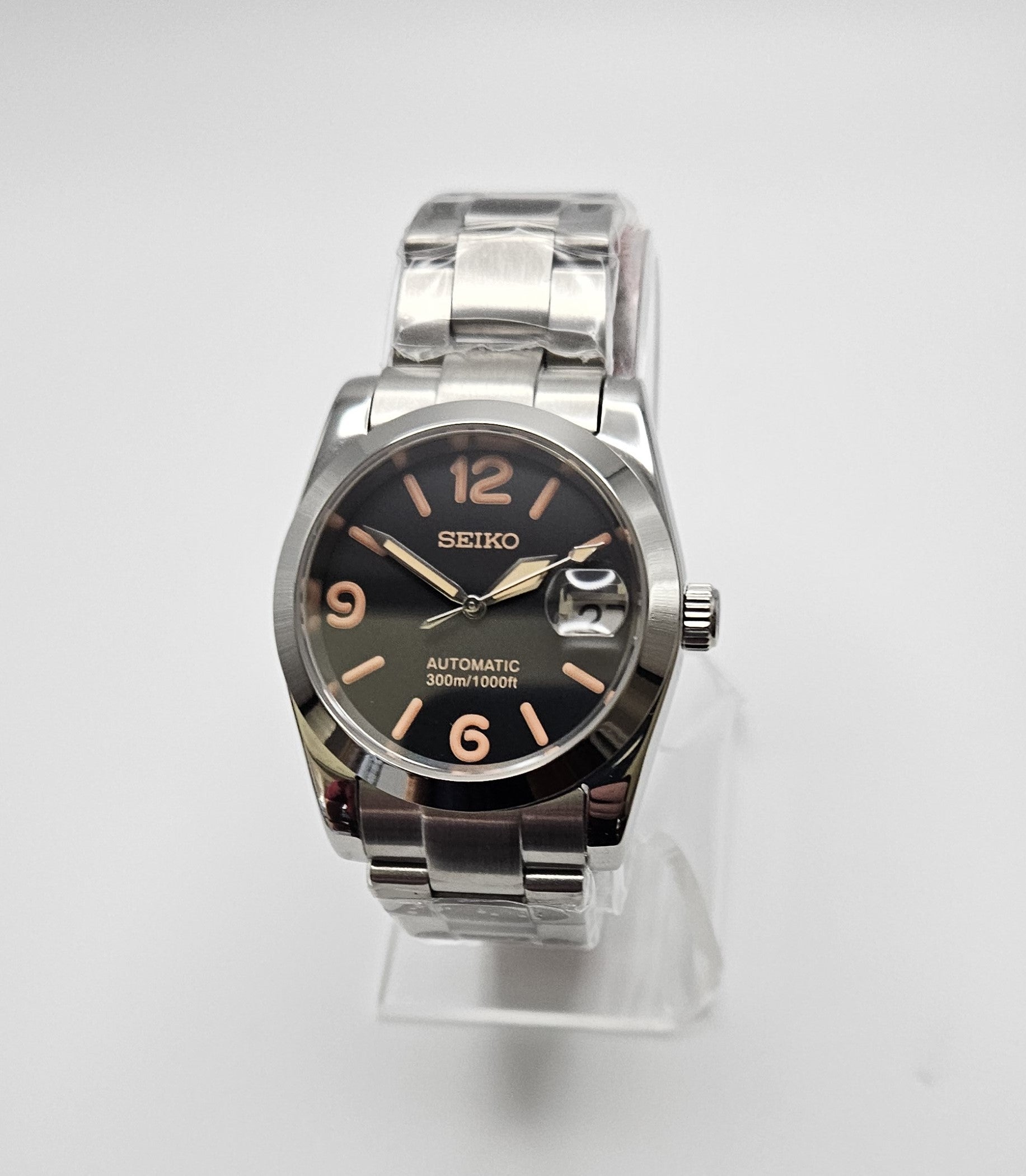 Silver Seiko watch with black dial on a white background