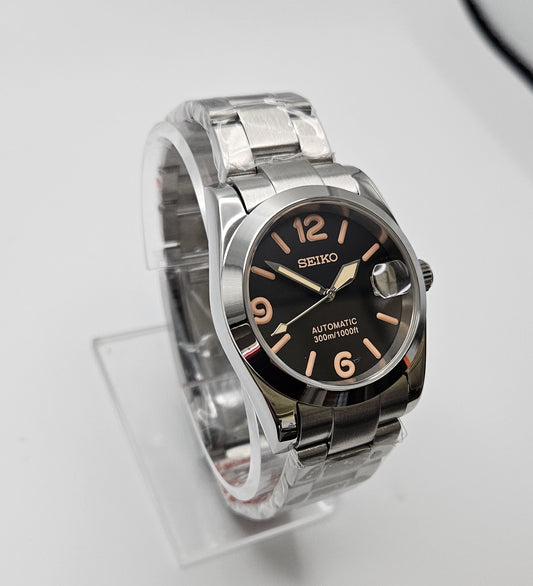 Seiko watch with black dial and silver metal band on a light gray background