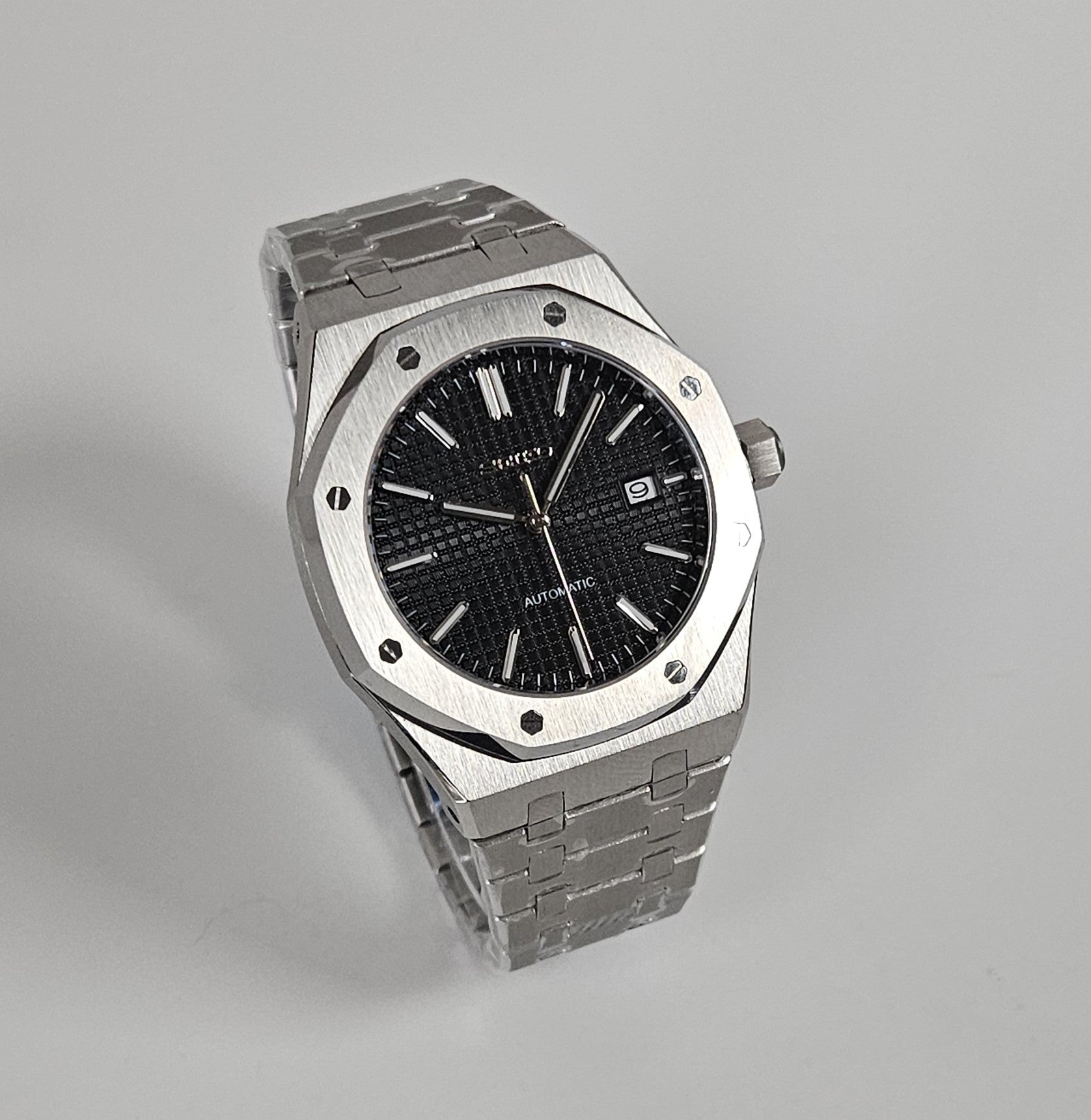 A black dial Royal Oak Seiko Mod watch with a stainless steel bracelet and a screw down case back.