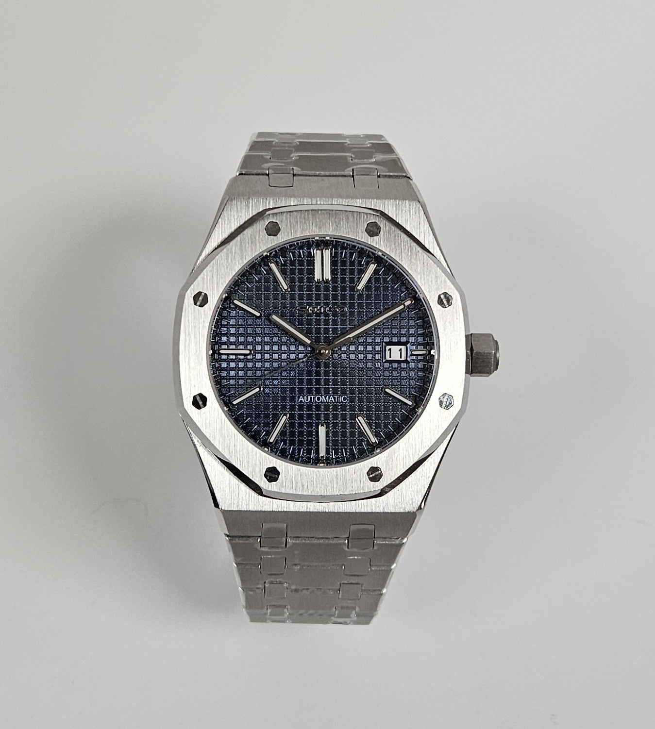 A black dial Royal Oak Seiko Mod watch with a stainless steel bracelet and a screw down case back.