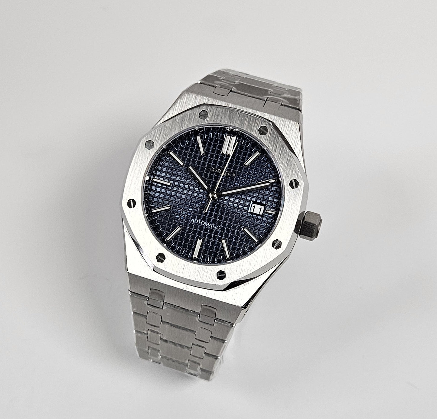 A black dial Royal Oak Seiko Mod watch with a stainless steel bracelet and a screw down case back.