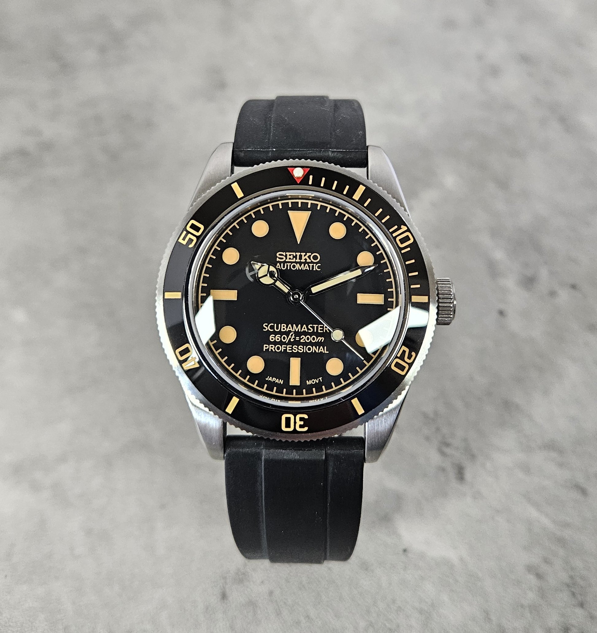 Seiko watch with black strap on a gray background