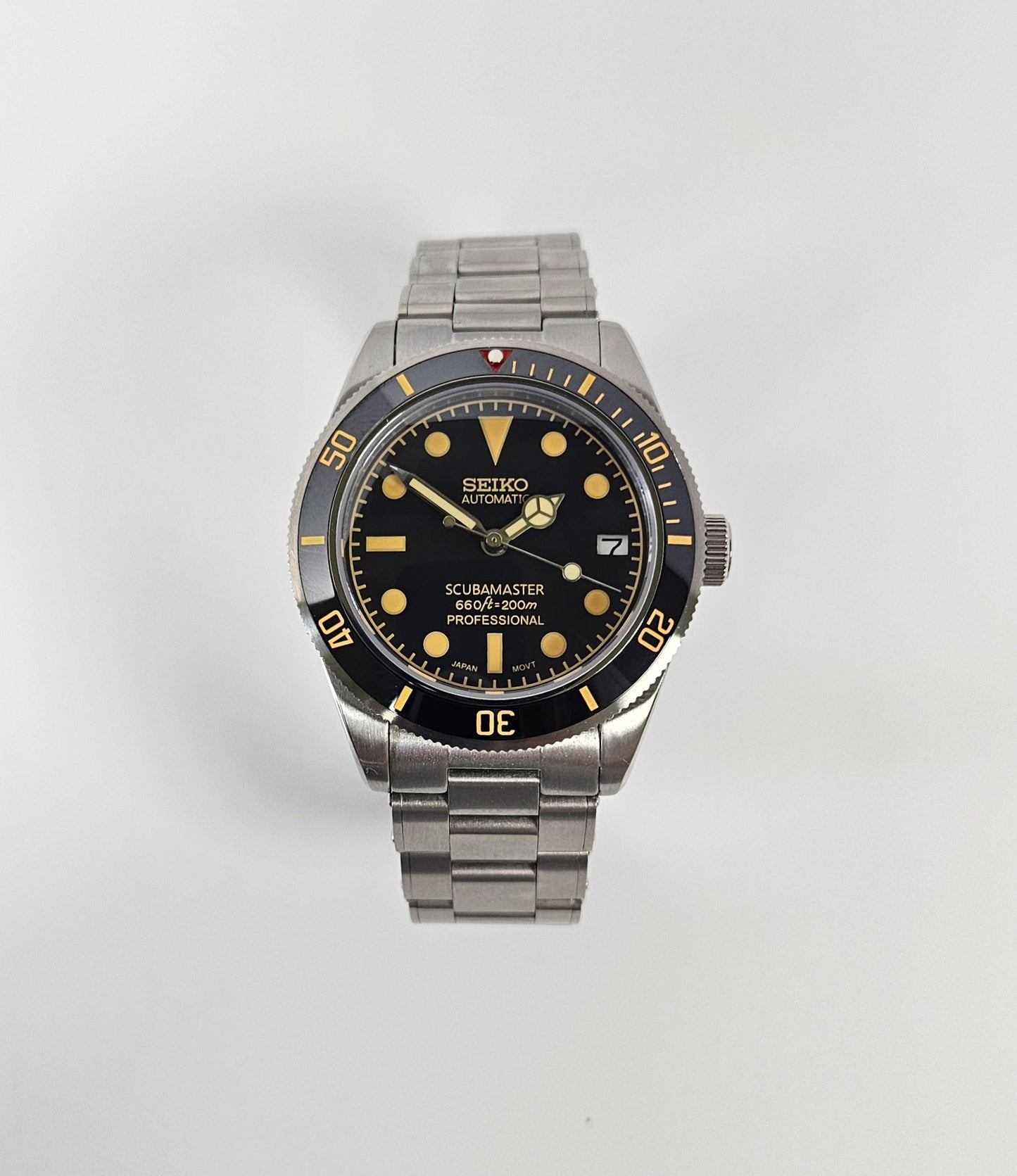 Seiko watch with black dial and silver metal strap on a white background