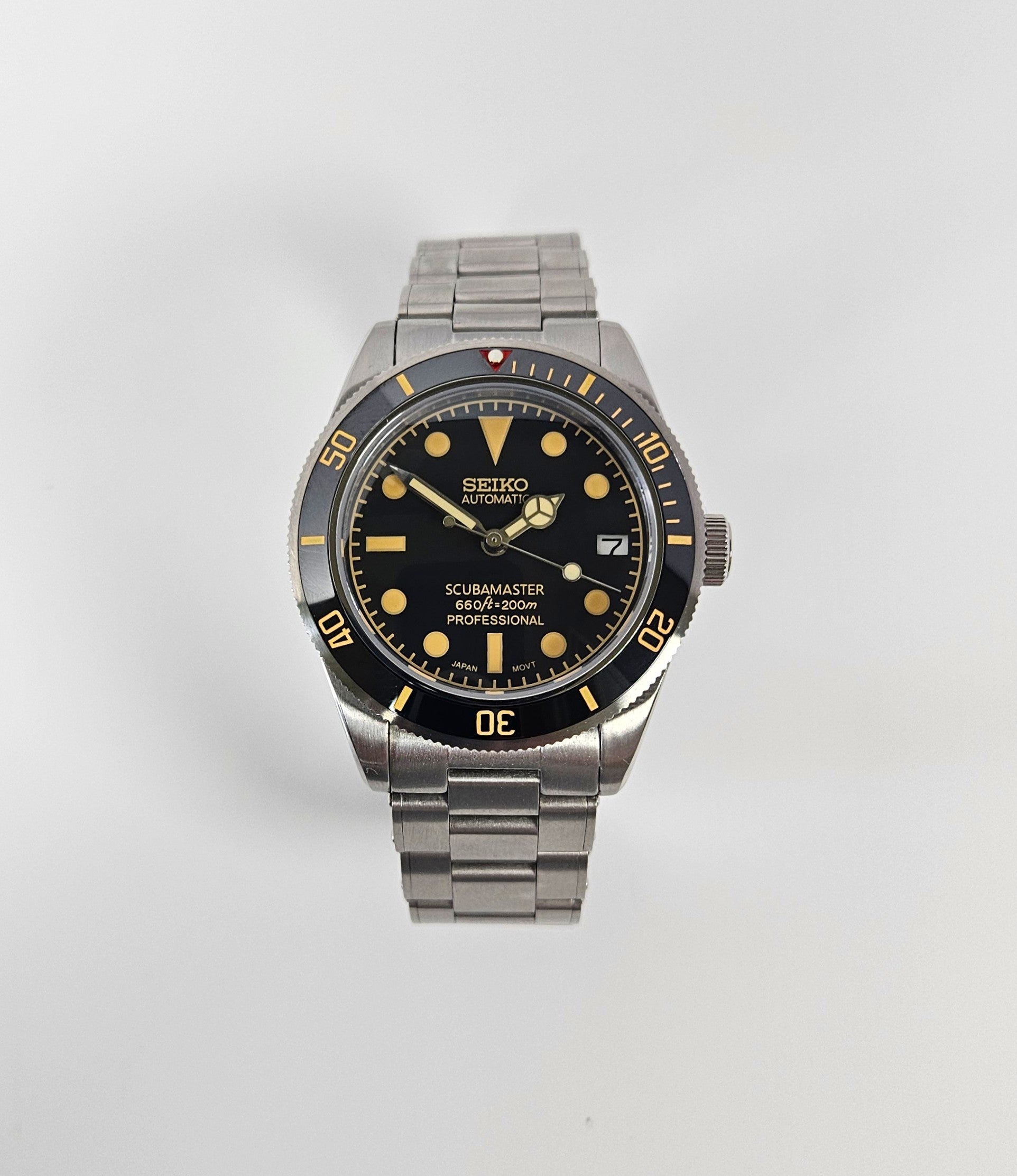 Seiko watch with black dial and silver metal strap on a white background