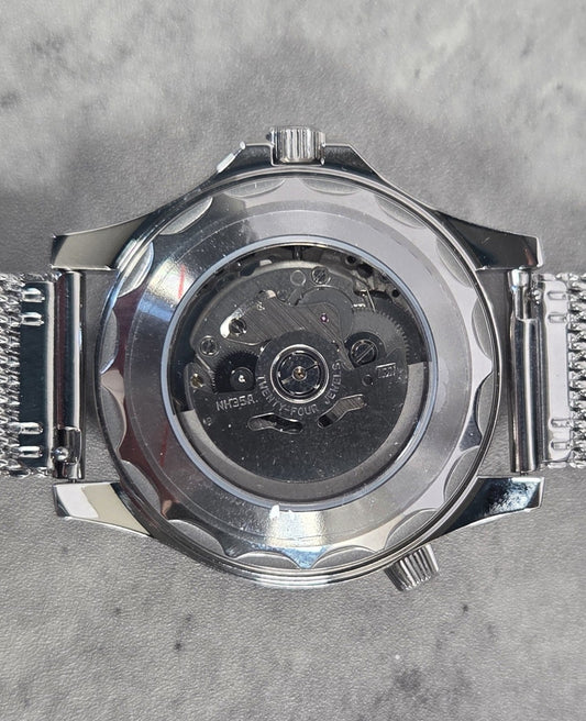 Silver watch with mesh band on a gray textured background