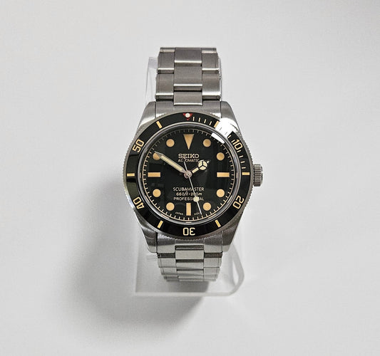 Seiko watch with black dial and silver metal strap on a light gray background